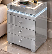 A MODREN BEDSIDE SIDETABLE IN CRYSTAL FINISH WITH LIGHT AND PHONE CHARGING OPTION AND 3 DRAWERS. MEASUREMENTS 45X40X60CM