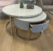 NESTING COFFE TABLE SET 80+60 CM FEATURES A WHITE MARBLE EFFECT TOP WITH GREY DRAWERS AND SILVER LEGS.