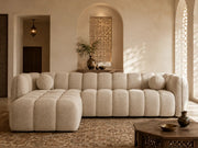 A BEIGE BOUCLE SECTIONAL SOFA WITH ROUNDED , CHANNEL TUFTED CUSHIONS AND A DEEP CHAISE . MEASUREMENT 314X175CM