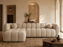 A BEIGE BOUCLE SECTIONAL SOFA WITH ROUNDED , CHANNEL TUFTED CUSHIONS AND A DEEP CHAISE . MEASUREMENT 314X175CM