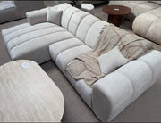 A MODREN BEIGE L-SHAPED SECTIONAL SOFA IN BEIGE  WITH SOFT TEXTURED FABRIC AND ROUNDED ARMRESTS.MEASURING 270X160CM