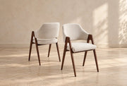A modern armchair with a cream upholstered seat and back, dark walnut wooden frame, tapered legs, and sculptural open arms.