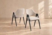 A modern armchair with a cream upholstered seat and back, BLACK wooden frame, tapered legs, and sculptural open arms.